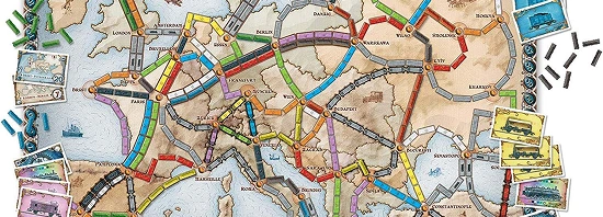 Karty do gry Wsiąść do Pociągu: Europa i kolorowe pionki pociągów ułożone na stole podczas rozgrywki.